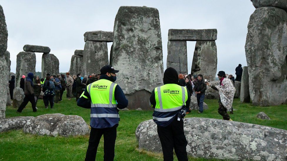 Security looks on as people gather at Stonehenge ancient stone circle during the Summer Solstice celebrations