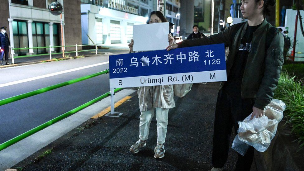 Протестующий держит знак протеста в Токио