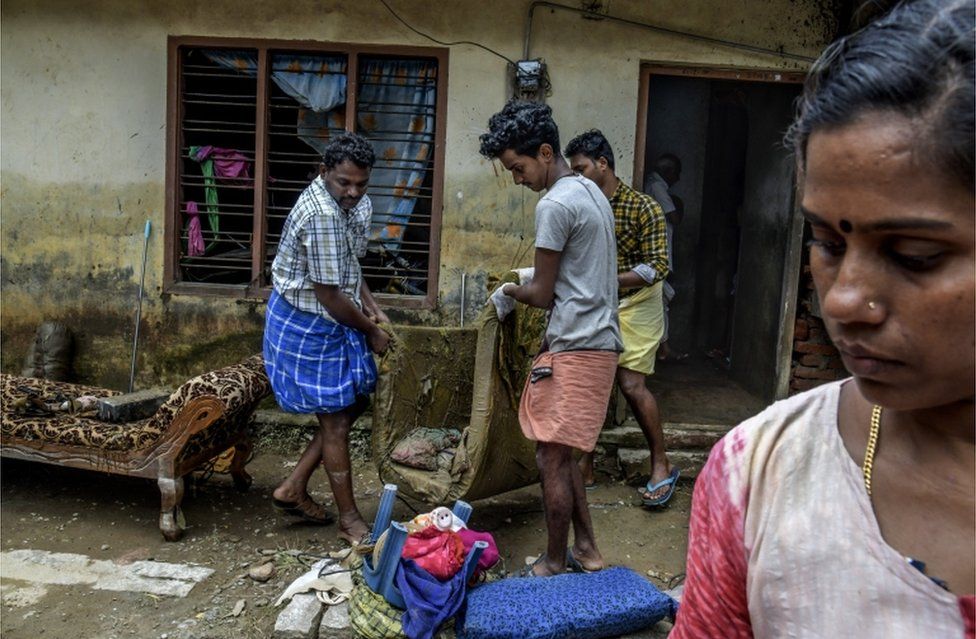 Семья пытается очистить свой затопленный дом в деревне Мунданкаву в Керале, Индия