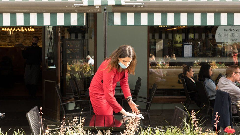 Официантка убирает столик возле ресторана в Сохо, Лондон
