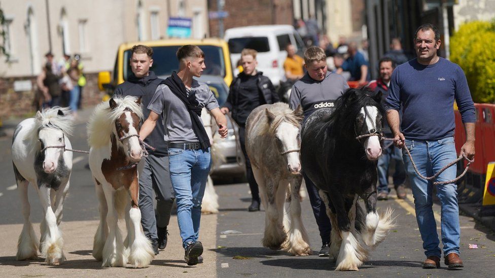 Four horses being walked through the town