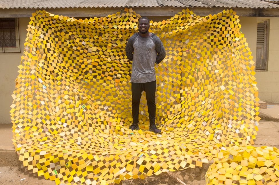 Serge Clottey standing on one of his tapestries in La - Accra, Ghana