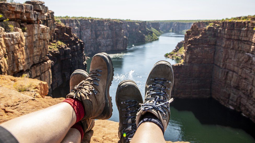 Feet of two backpackers over a river in Australia
