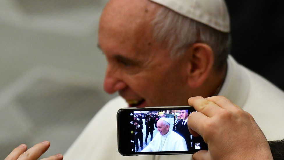 someone takes a photo of the pope with their mobile