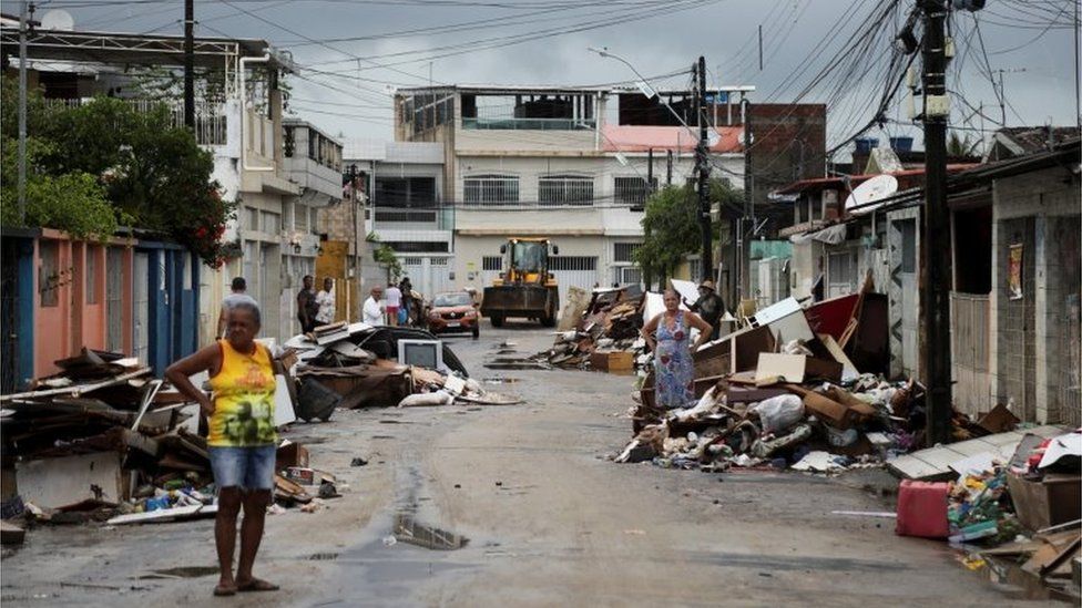 Люди стоят среди обломков домов, пострадавших от проливных дождей, в районе Кокейрал, Ресифи, Бразилия , 31 мая 2022 г.
