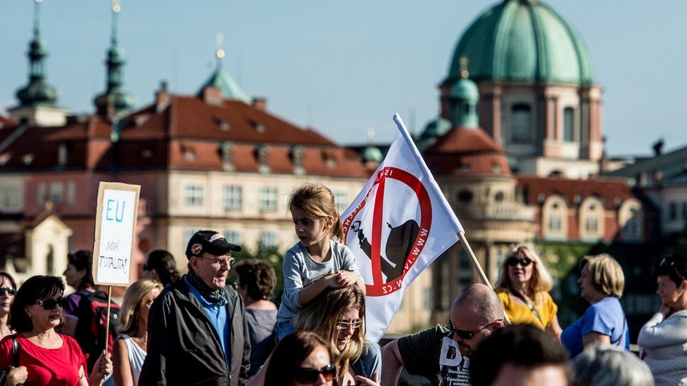 Protesters in Prague hold up an anti-Islam banner and a placard opposing binding EU quotas for taking in refugees