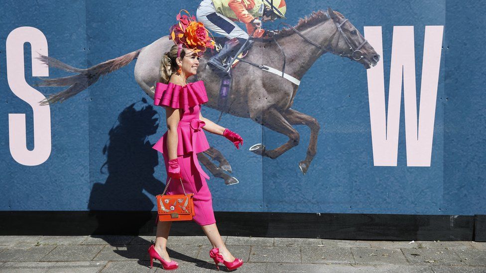 Woman in front of a picture of a jockey and horse at Aintree