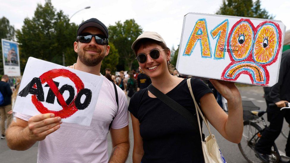 Protesters hold signs with A100 crossed out