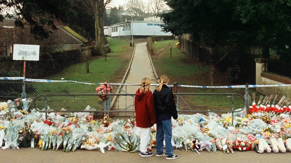 Children view flowers laid at the gates of Dunblane Primary School following the 1996 shooting
