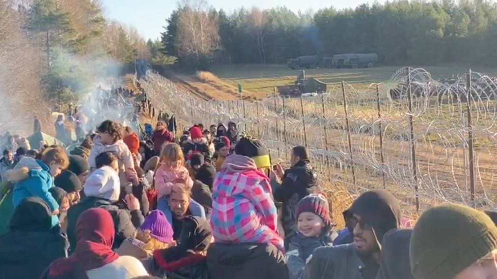 Мигранты собираются у забора из колючей проволоки на польско-белорусской границе в Гродненском районе Беларуси