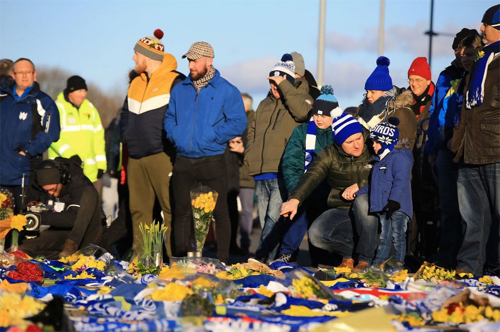 Fans place flowers and T-shirts with messages in tribute of Emiliano Sala before Cardiff's Premier League match against Bournemouth at the Cardiff City Stadium on Saturday