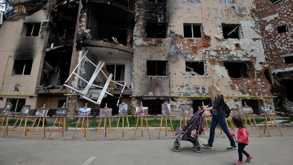 A woman and her daughter walk past a destroyed residential building in Irpin, near Kyiv. Photo: 16 June 2022