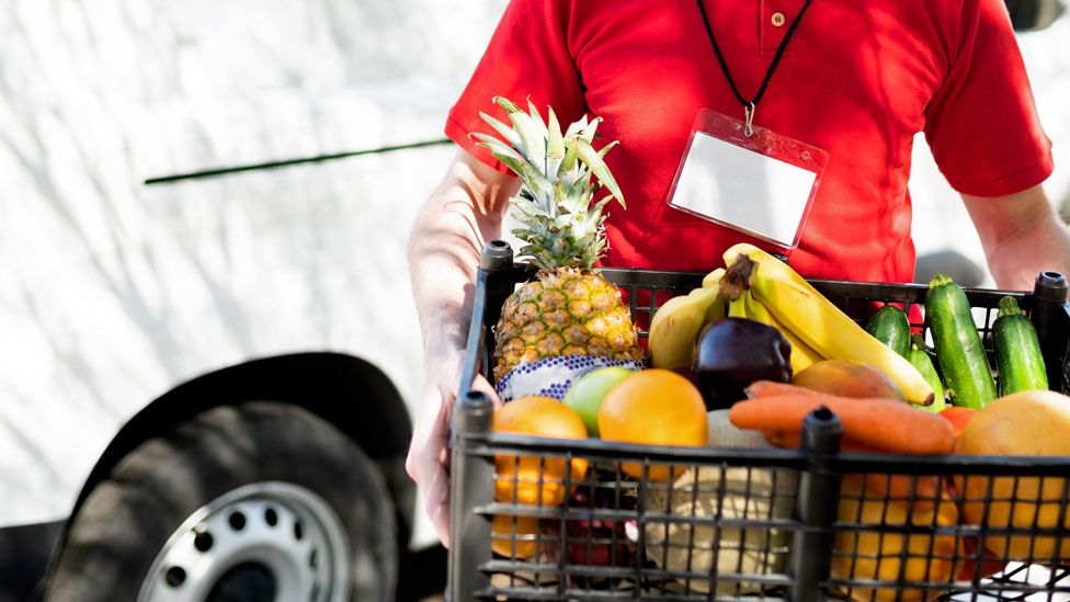 Stock image of a food delivery person standing in front of a van
