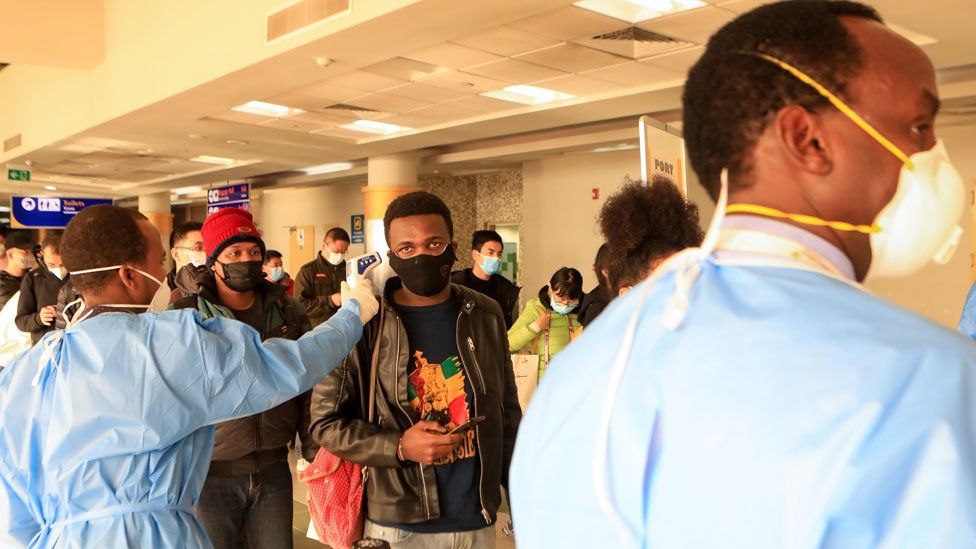 Passengers wearing face masks queue to be screened after arriving from China at Jomo Kenyatta International Airport