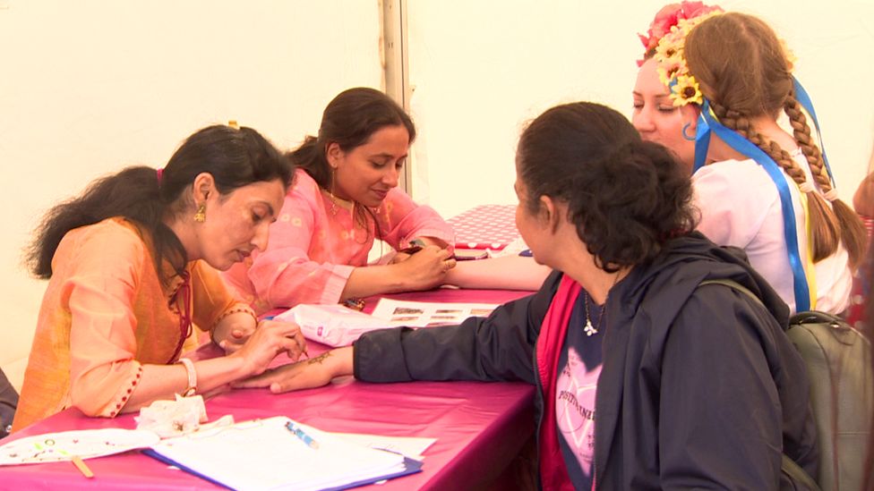 Women give parade goers Henna tattoos