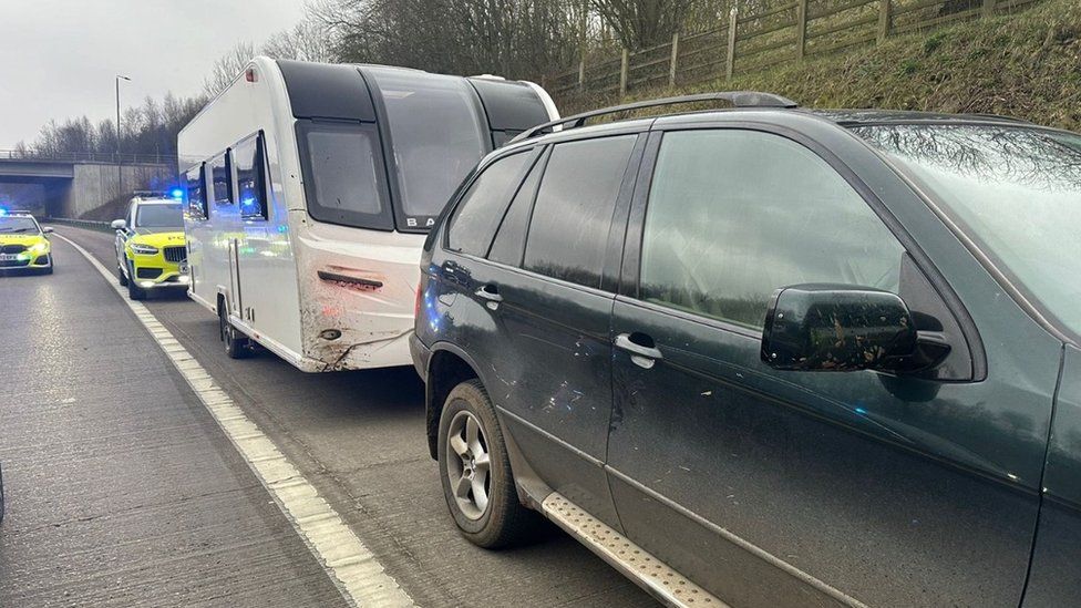 Car towing a caravan being followed by police cars