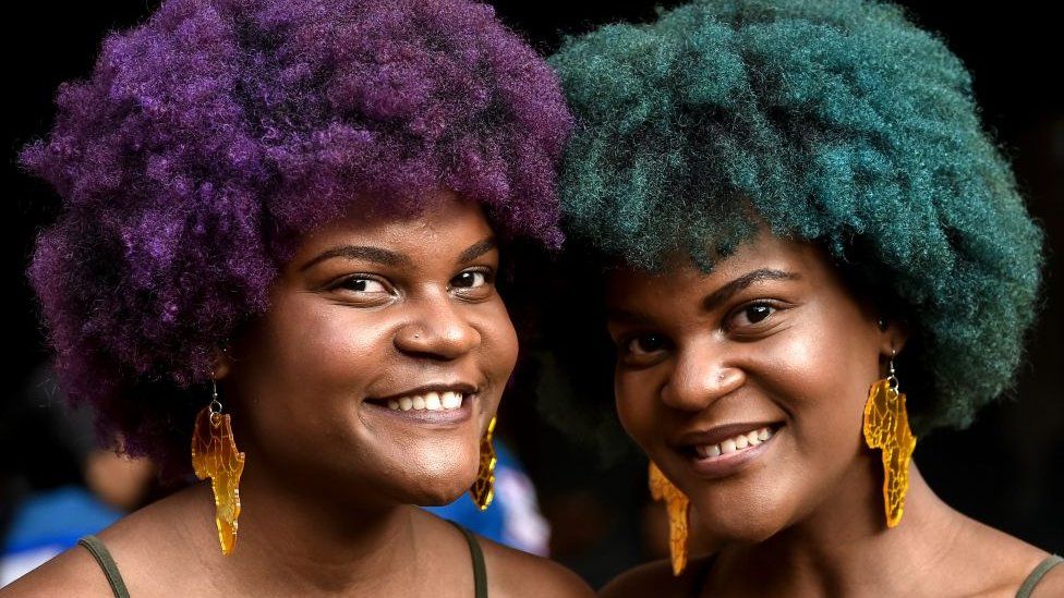 Two women with brightly coloured Afro hair