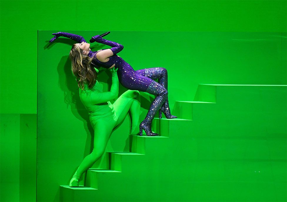 Eurovision participant Stefania of Greece is held up by someone in a green costume at the final of the 2021 Eurovision Song Contest in Rotterdam, Netherlands.