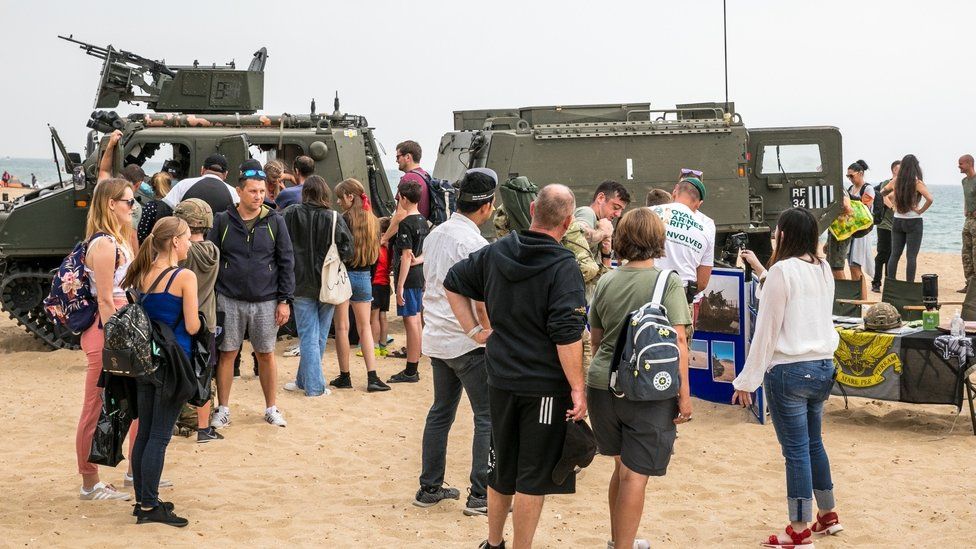 People on the beach watching the army display