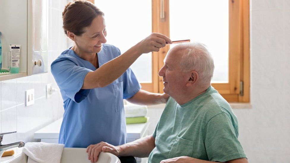 Home Caregiver with senior man in bathroom - stock photo