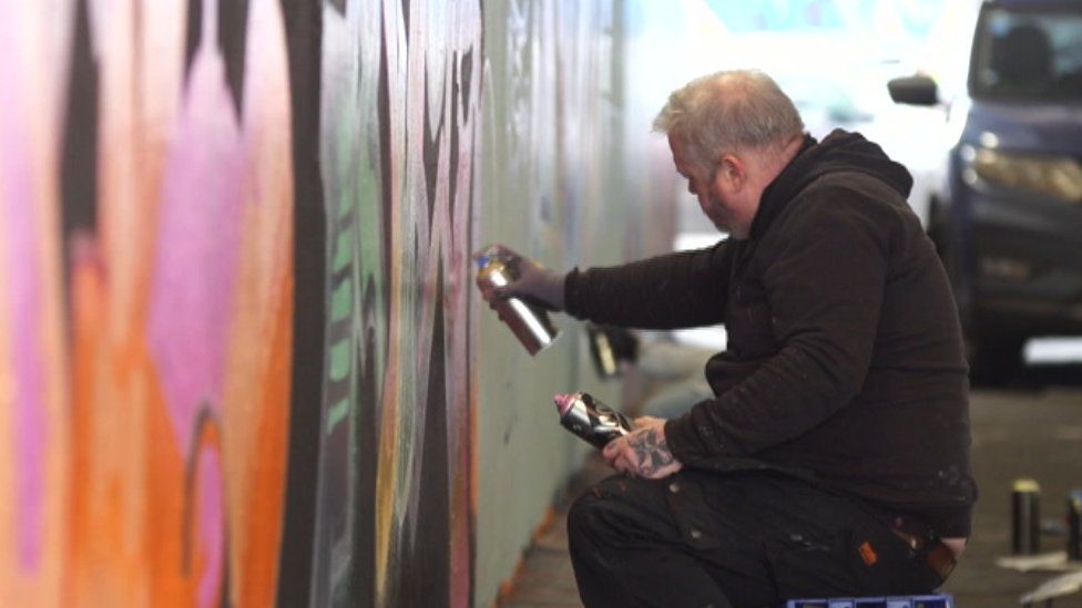 A graffiti artist painting a wall