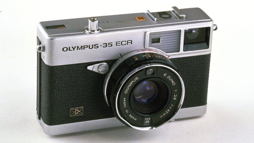 An Olympus-35 ECR rangeinfer-style camera with a short "pancake" lens is seen here against a white background
