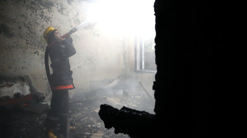 A firefighter battles a fire at a residential building damaged in a shelling attack in Azerbaijan