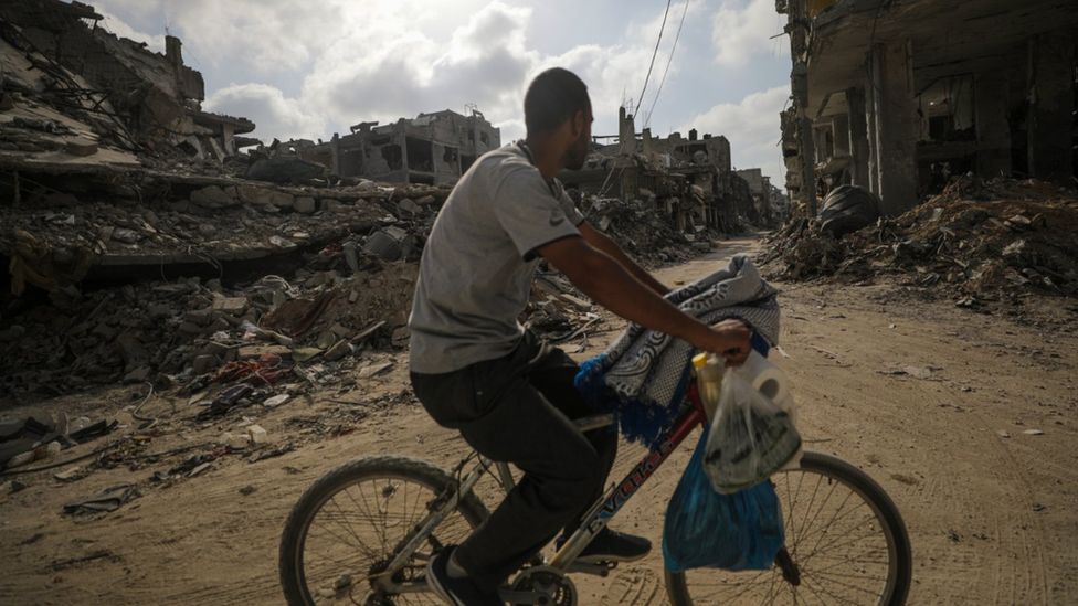 A Palestinian man cycles past destroyed buildings in Khan Younis after the Israeli military pulled out troops from the southern Gaza Strip, 30 April 2024.