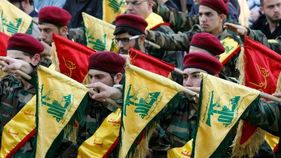 Members of Lebanon's Hezbollah movement hold up flags as they march during the funeral of a fighter in Kfour (1 March 2016)