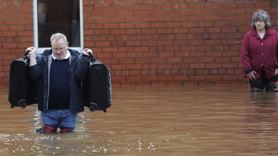 Residents carry possessions from their flooded homes in Carlisle