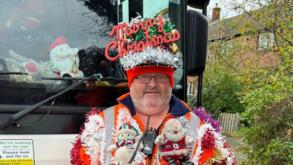 Bearded man with Merry Christmas hat and tinsel around his coat