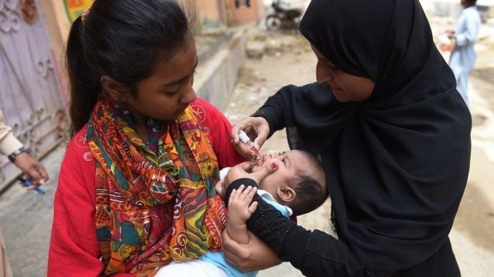 Pakistani health worker administers polio drops to a child in Karachi