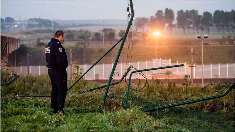 A policeman stands by a breached fence at the Eurotunnel terminal