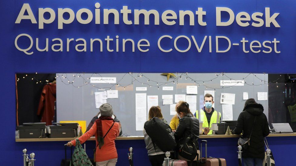 People wait in front of an "Appointment Desk" for quarantine and coronavirus disease (Covid-19) test appointments inside Schiphol Airport
