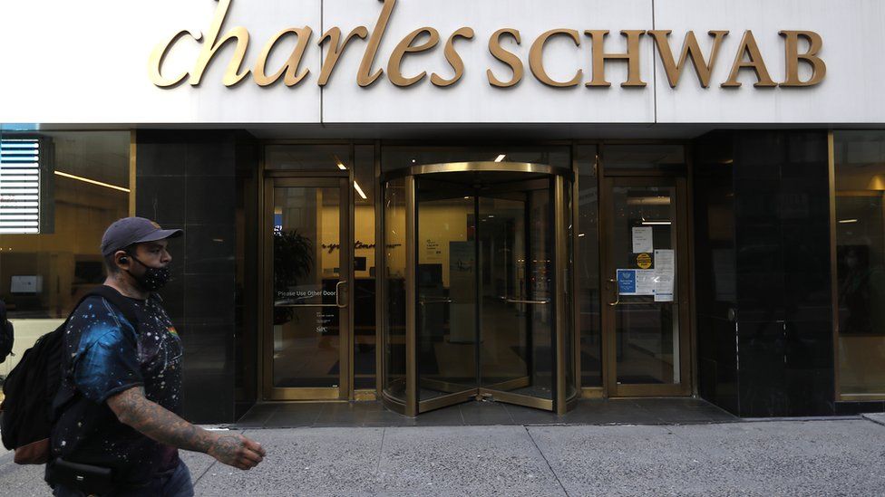 man in mask walks past Charles Schwab