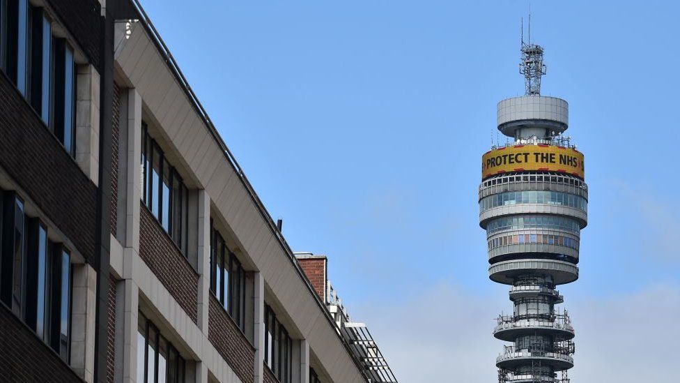 London's BT tower is seen rising above the buildings around it, with satellite dishes and communications equipment dotted around its circumference