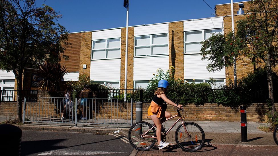 A child cycle past Corpus Christi Catholic School in London, 4 September 2023