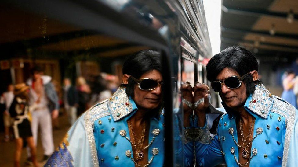 An Elvis Presley impersonator leans against the Elvis Express train at Sydney Central Railway Station