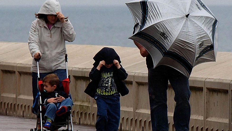 A family with umbrella battles wind