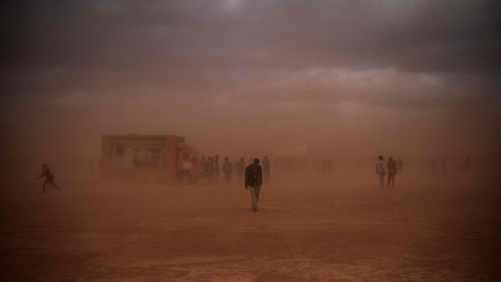 People walking to the mass in the dust