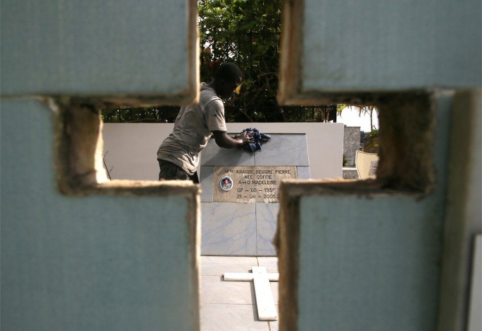 A man cleans a grave at the Williamsville cemetery in Abidjan.