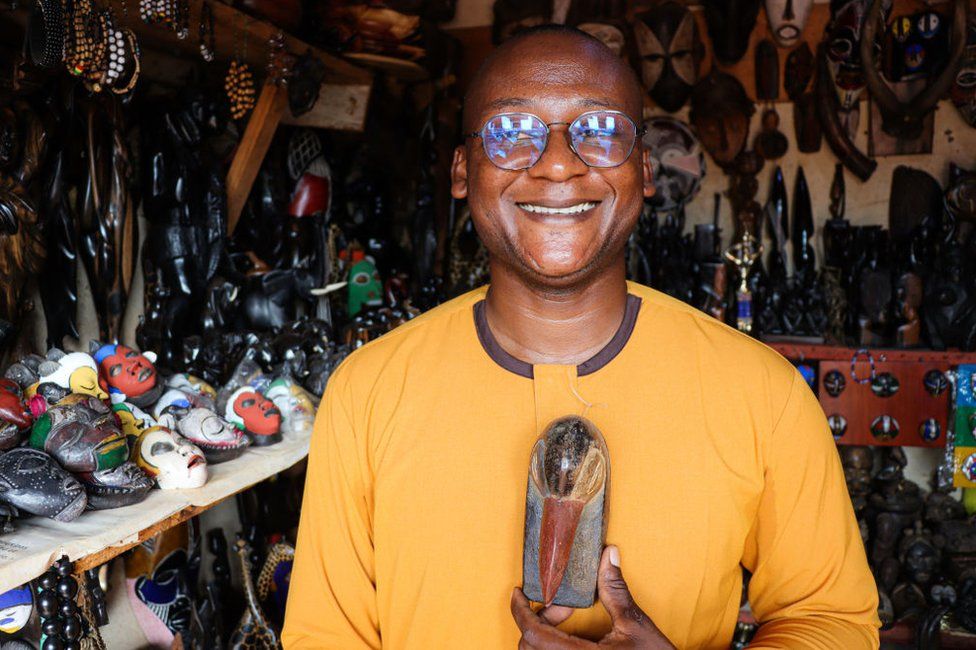 A man poses with artisanal goods in a kiosk in Yaounde, Cameroon.