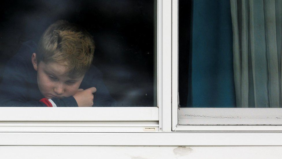 Blonde boy behind white-framed window