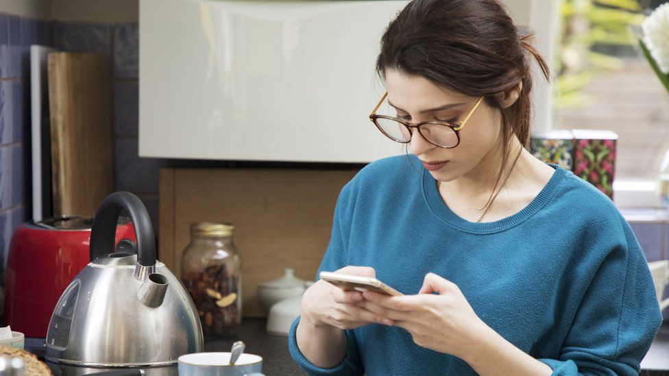 Woman on phone boiling kettle