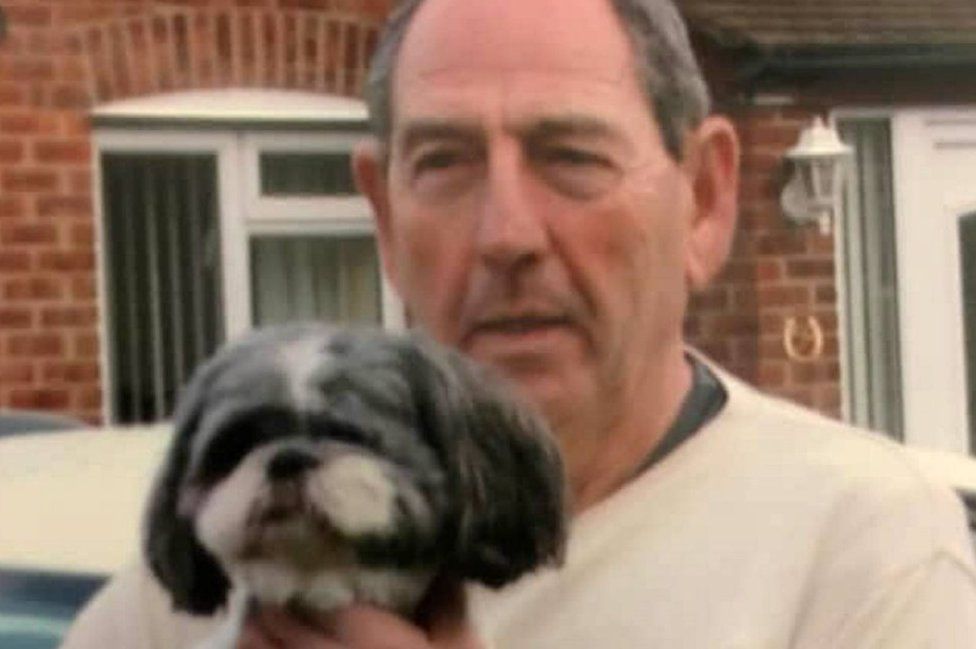 A man holds a small terrier type dog