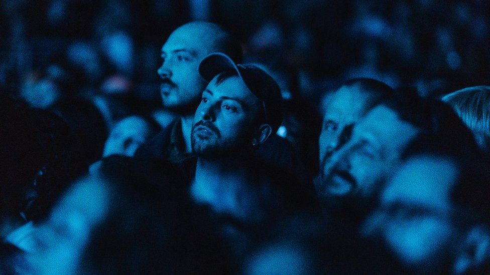 Music fans watch Fever Ray at Bristol Beacon, illuminated by blue lights