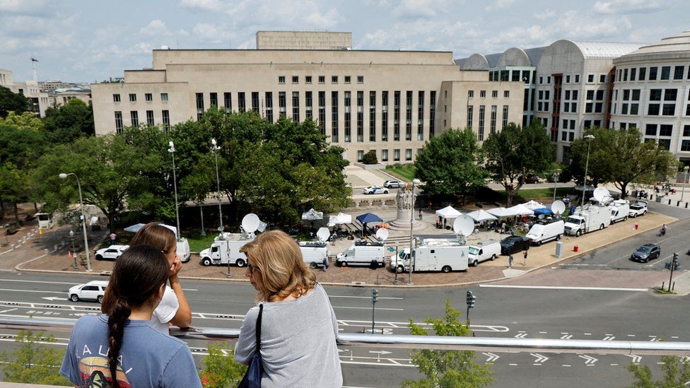 Tourists atop the National Gallery of Art look out over the news trucks in front of the federal courthouse where former U.S. President and Republican presidential candidate Donald Trump is expected to answer charges after a grand jury returned an indictment of Trump in the special counsel's investigation of efforts to overturn his 2020 election defeat In Washington, U.S. August 2, 2023.