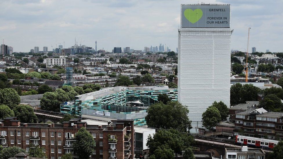 A sign with "Grenfell Forever In Our Hearts" is displayed on the top of Grenfell Tower