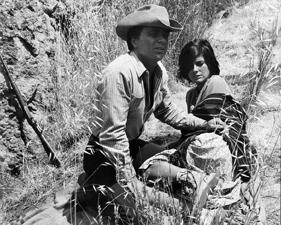 Роберт Блейк сидит на земле с Кэтрин Росс в сцене из фильма «Скажи им, что мальчик Вилли здесь», 1969 год.