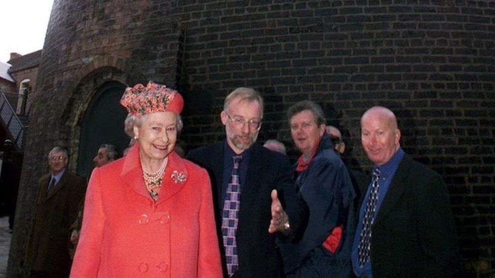 The Queen with a group of men next to a kiln